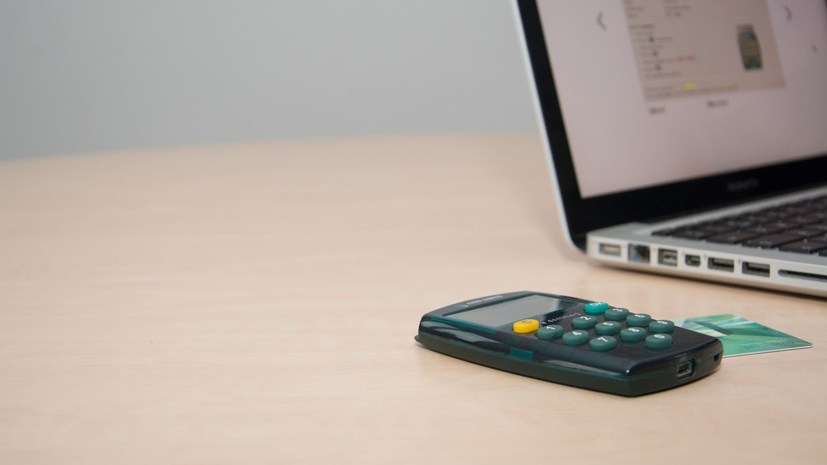 Calculator and credit card next to a laptop