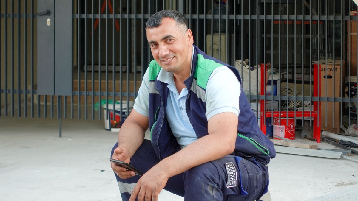 Construction worker smiling while using a smartphone on site
