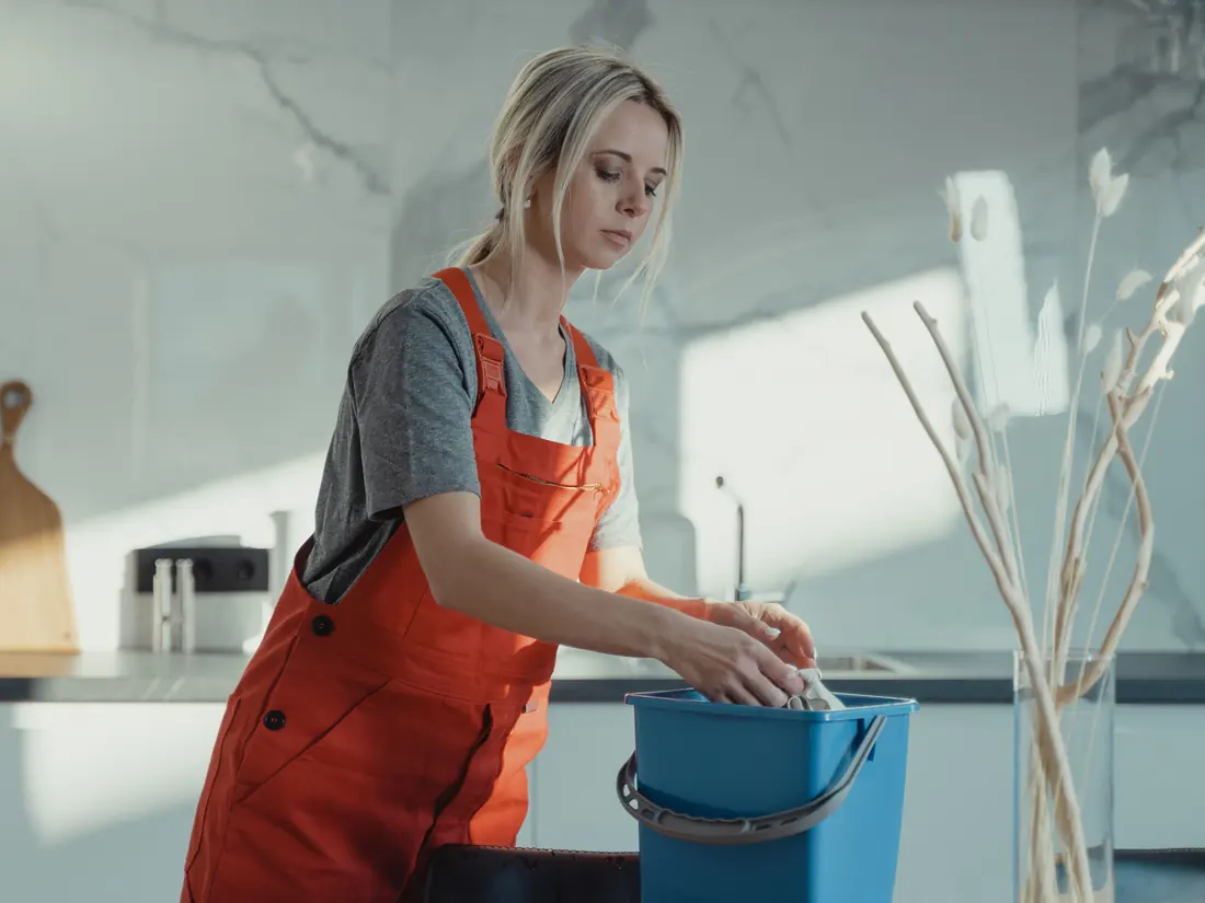 Cleaner wiping down a kitchen bench