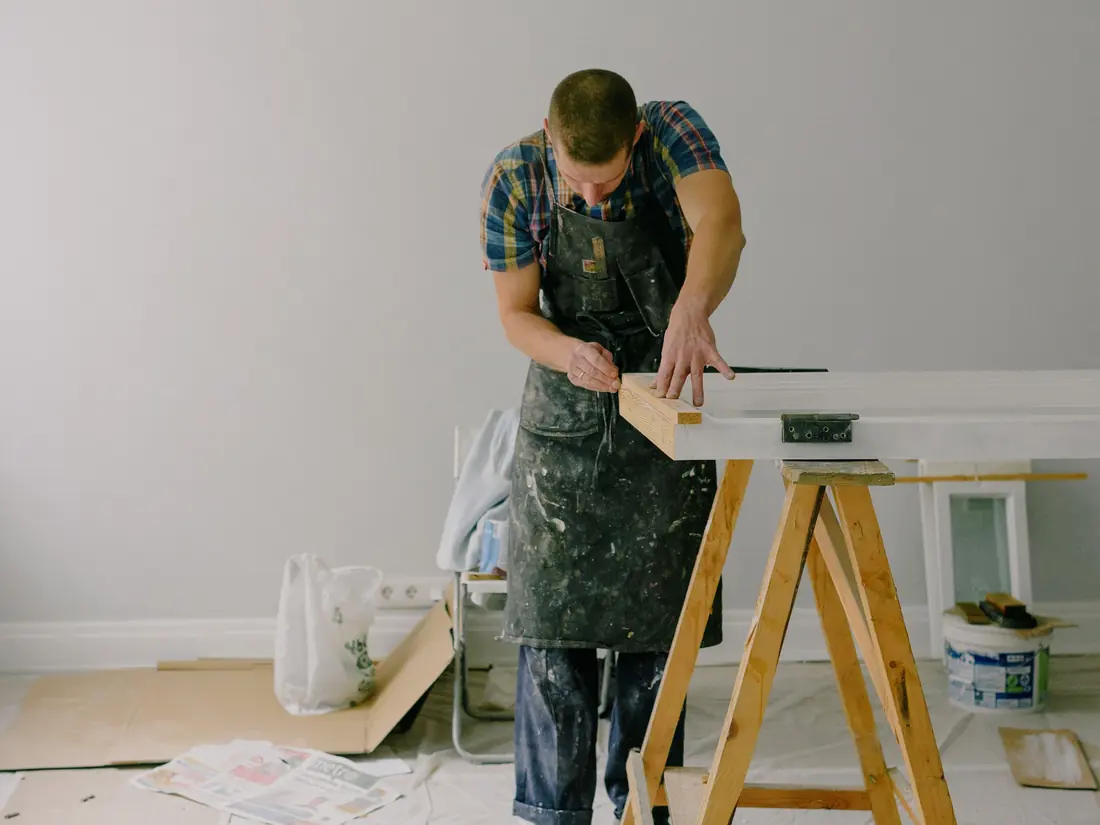 Handyman measuring a length of timber on a sawhorse