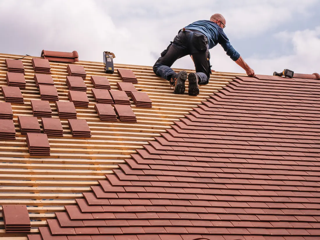 Roofer laying tiles on a new roof