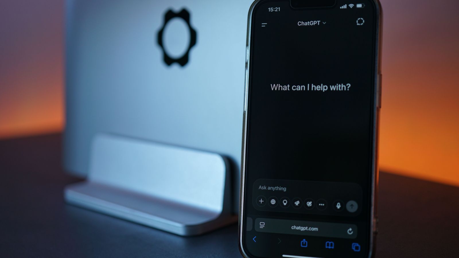 Smartphone displaying a chat interface beside a laptop.