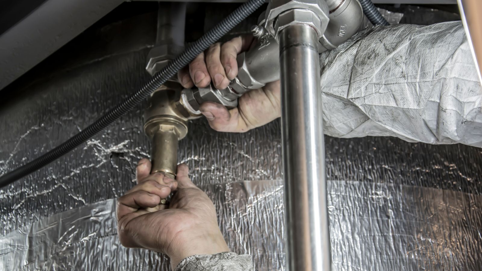 Hands installing metal pipe fittings in a commercial system.